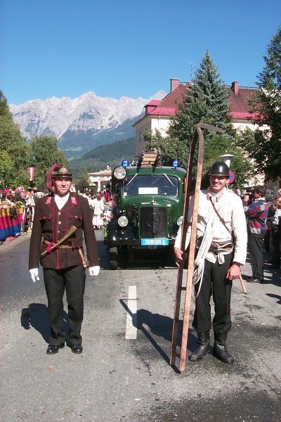 Historische Feuerwehruniformen, dahinter Lschfahrzeug Mercedes Baujahr 1942